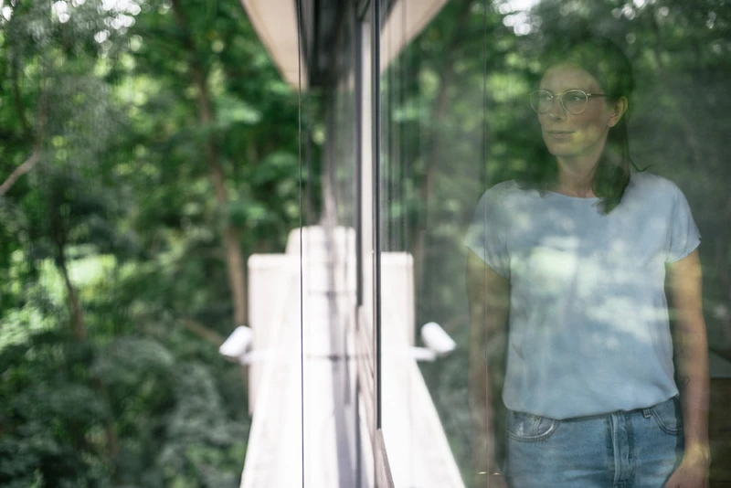 Frau steht vor fenster und schaut nach drau&szlig;en