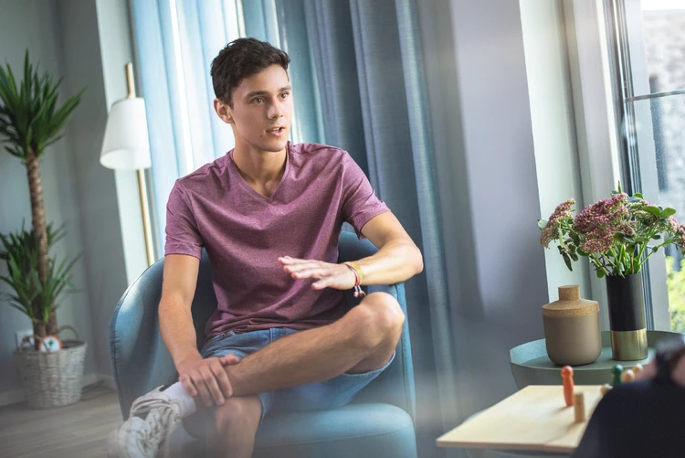 Junger mann sitzt energie geladen auf einem stuhl